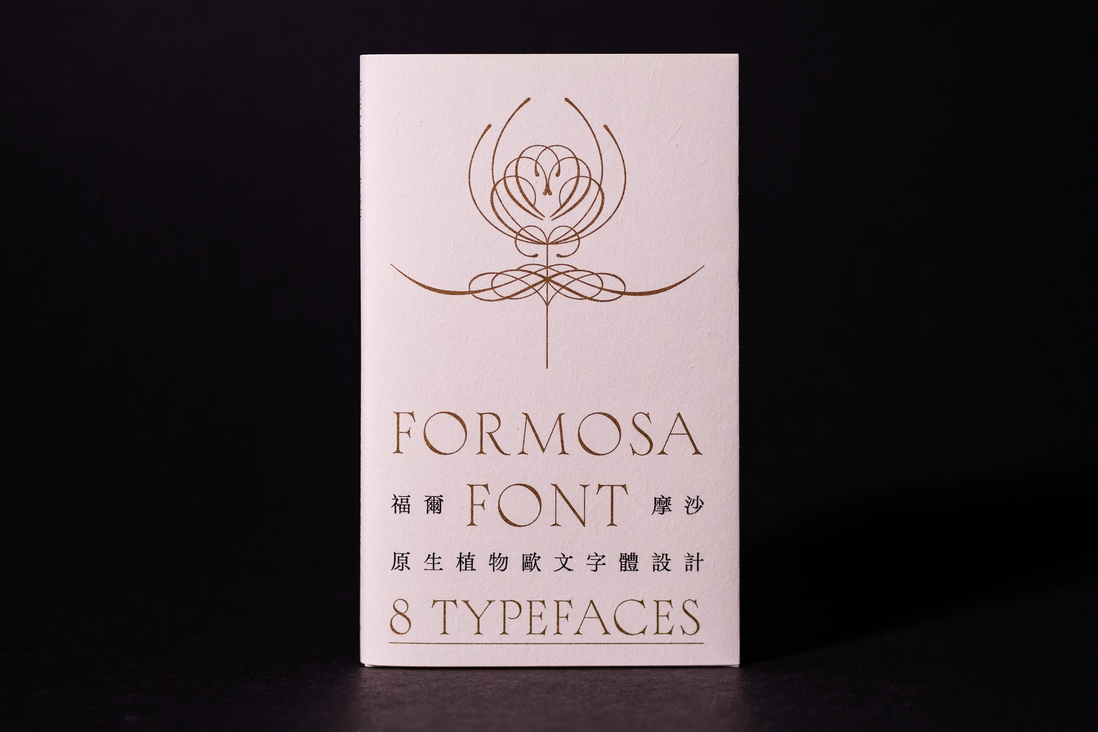 A cream-white booklet cover set against a dark background, featuring an ornate gold botanical line illustration above the bilingual title "Formosa Font / 福爾摩沙 FONT" and the subtitle "8 Typefaces / 原生植物歐文字體設計," rendered in elegant gold serif and sans-serif lettering.