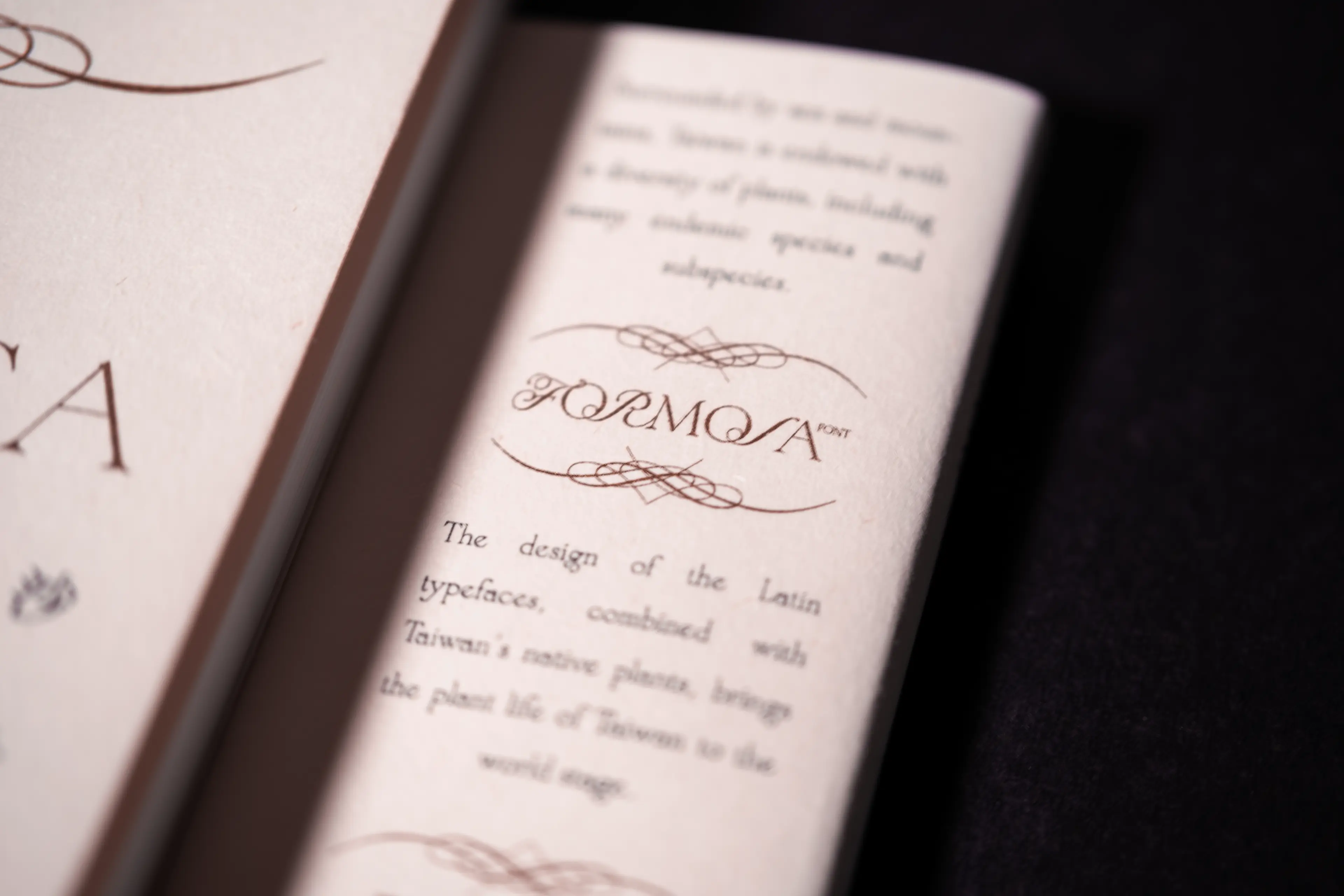 An open book spread with cream-colored pages, featuring the ornate "FORMOSA" logotype surrounded by decorative calligraphic flourishes printed in dark brown ink. Body text in an elegant serif typeface reads about the design combining Latin typefaces with Taiwan's native plant life.