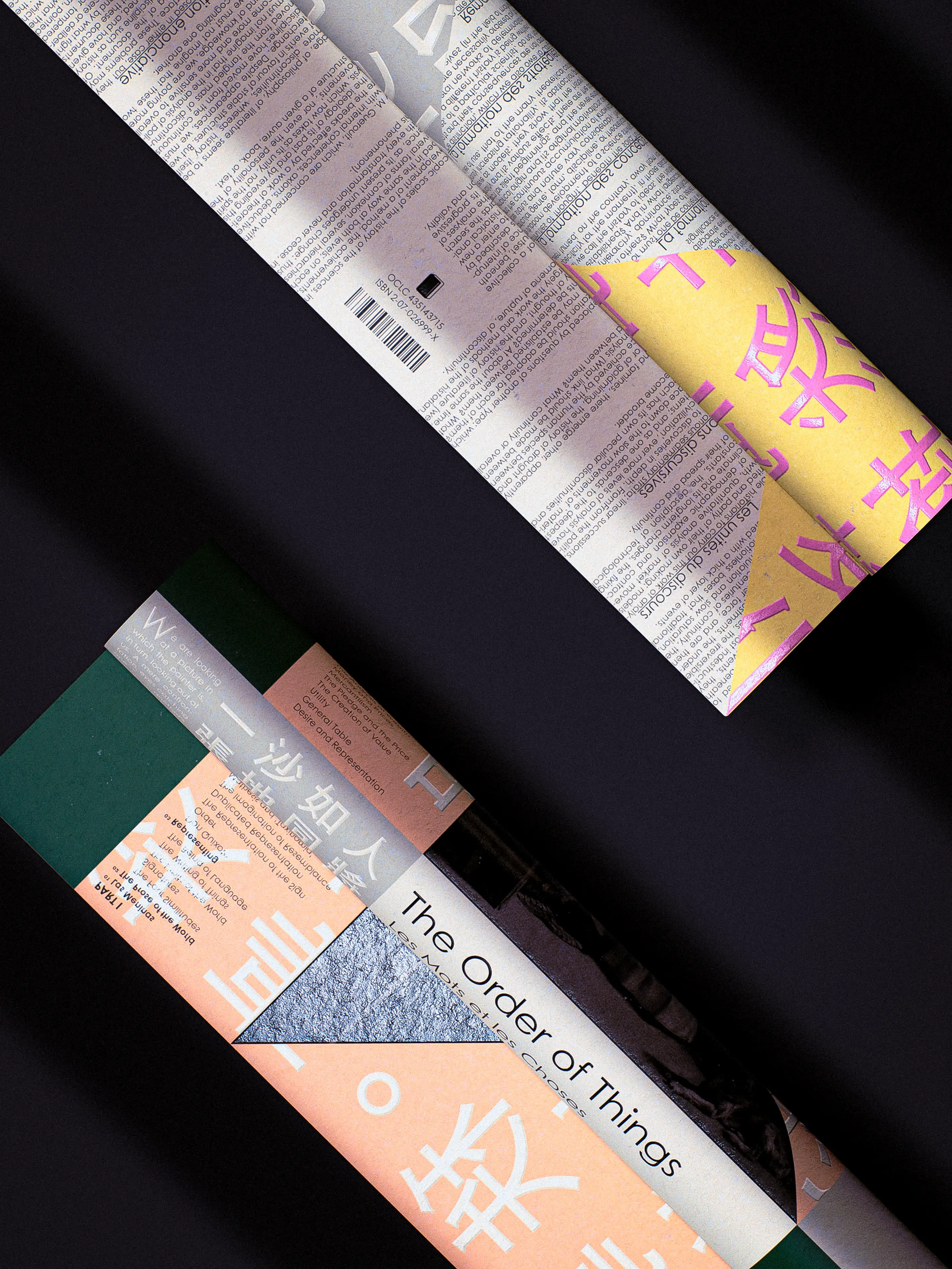 Two Foucault book designs are laid diagonally on a dark surface — the upper book features dense newsprint-style text with a yellow panel printed with large pink Chinese characters, while the lower book displays a geometric color-block cover in salmon, teal, and grey with the title "The Order of Things" in clean sans-serif type alongside Chinese typography.