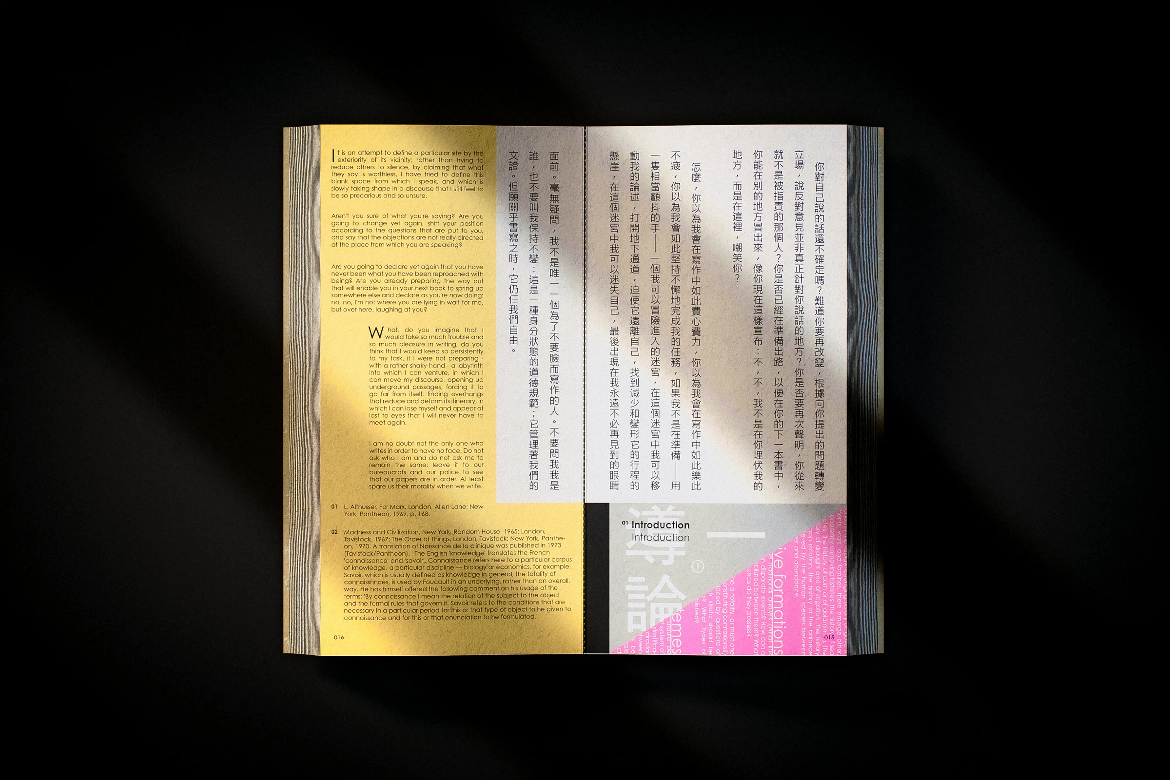 An open book spread featuring bilingual text layout in English and Traditional Chinese, with a warm gold-toned left page and a white right page. A bold pink and grey geometric section divider marks an "Introduction" chapter, with large Chinese characters overlaid in a structured typographic composition.